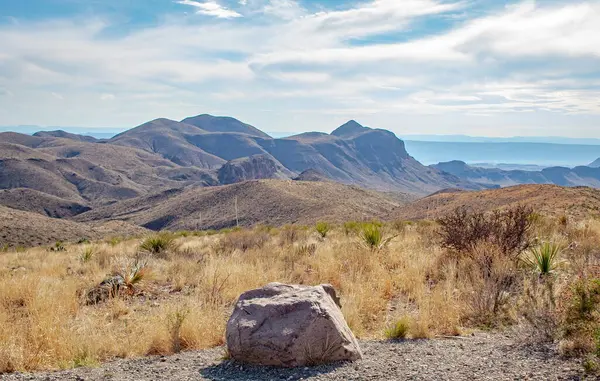 Texas 'taki Big Bend Ulusal Parkı' nda kaya, dağ ve çöl çim manzarası. Fotoğraf bulutlu mavi bir gökyüzünde çekildi.