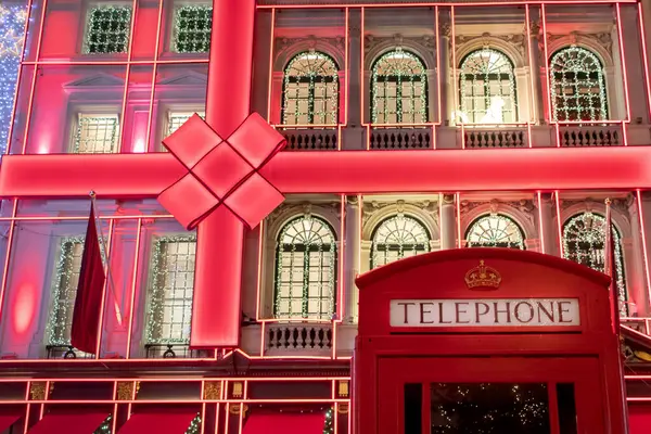 Aydınlatılmış, dekore edilmiş mağaza önü ve sembolik kırmızı Londra telefon kulübesi. Fotoğraf Londra 'da, İngiltere' de Noel zamanı çekildi.