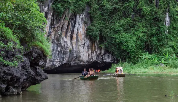 Tropik yemyeşil ormanlar ve dağlarla çevrili bir nehirde yüzen insanlar. Tam Coc Ninh Binh Vietnam 'da.
