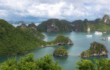 Bereketli tropikal bitkiler, ada kireçtaşı dağları, mavi su ve Vietnam 'daki Halong Körfezi' ndeki okyanus denizi boyunca uzanan tekneler.