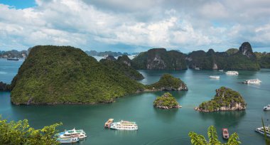 Bereketli tropikal bitkiler, ada kireçtaşı dağları, mavi su ve Vietnam 'daki Halong Körfezi' ndeki okyanus denizi boyunca uzanan tekneler.