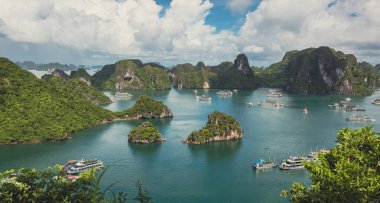 Bereketli tropikal bitkiler, ada kireçtaşı dağları, mavi su ve Vietnam 'daki Halong Körfezi' ndeki okyanus denizi boyunca uzanan tekneler.