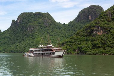Vietnam 'daki Halong Körfezi' nde tropik ada kireçtaşı dağları, su ve tekne manzarası.