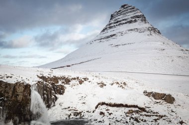 İzlanda 'nın Snfellsnes yarımadasında yer alan Kirkjufell Dağı karla kaplıydı. Fotoğraf, kışın bulutlu bir günde çekildi.