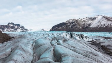 İzlanda 'daki Vatnajokull buzulunun güzel mavi buzulları ve dağları. Fotoğraf bulutlu bir günde çekildi. 