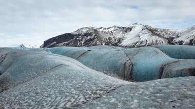 İzlanda 'daki Vatnajokull buzulunun güzel mavi buzulları ve dağları. Fotoğraf bulutlu bir günde çekildi. 