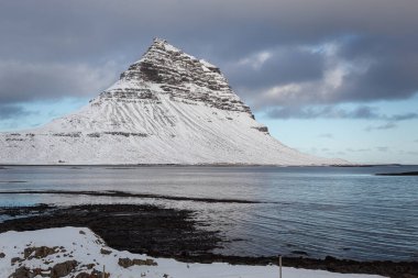İzlanda 'nın Snfellsnes yarımadasında yer alan Kirkjufell Dağı karla kaplıydı. Fotoğraf, kışın bulutlu bir günde çekildi.