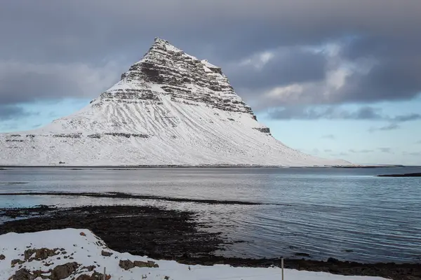 İzlanda 'nın Snfellsnes yarımadasında yer alan Kirkjufell Dağı karla kaplıydı. Fotoğraf, kışın bulutlu bir günde çekildi.