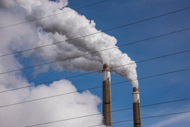 Kuzey düzlüklerinde, ön planda elektrik hatları olan, kömür atımlı enerji üretim istasyonundaki egzoz yığınları..