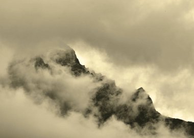 Bulutlar engebeli dağ zirvesini neredeyse karartacak, neredeyse gerçek üstü bir görüntü yaratacak..