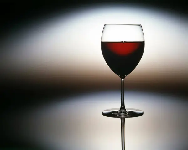 Yansıtıcı arka planda stilize edilmiş kırmızı şarap kadehi..