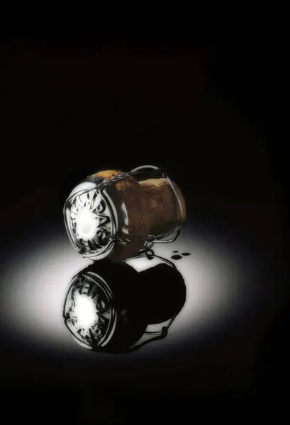 Şampanya mantarı ve kafesi siyah yansıtıcı arka planda..