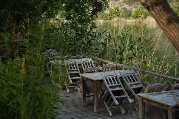 Sabahın erken saatlerinde Dalyan nehrinde kapalı bir kafe. Kırsal masa ve sandalyeler.