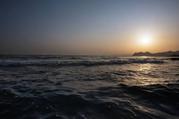 Gün batımında yavaşça kıyıya vuran dalgalar.