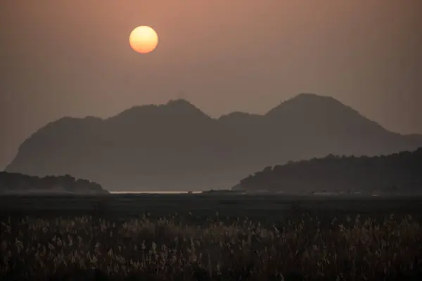 Dağların üzerinde açık gökyüzü günbatımı.