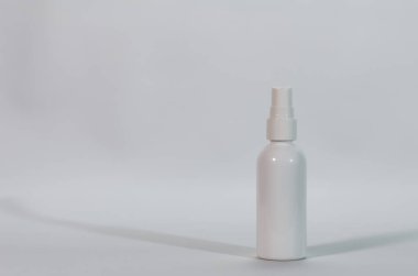 Minimalist tarafsız bir arkaplana karşı dimdik duran temiz, beyaz bir plastik sprey şişesi ince bir gölge oluşturur..