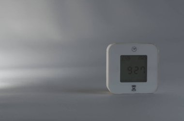 Saati ve tarihi gösteren dijital bir saat, minimalist, nötr gri bir arkaplana karşıdır. 