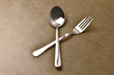 Mutfak tezgahında paslanmaz çelik çatal ve kaşık aranjmanı yemek ya da mutfak temalarını sembolize ediyor..