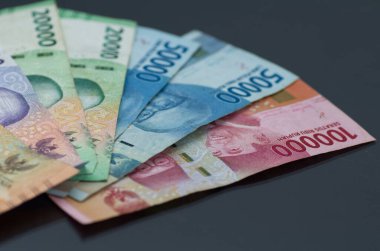 Endonezya Rupiah notlarının koyu bir yüzeye yerleştirilmiş renkli çeşitleri.