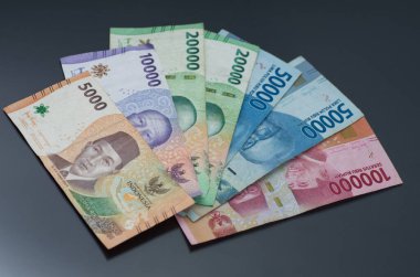 Endonezya Rupiah notlarının koyu bir yüzeye yerleştirilmiş renkli çeşitleri.