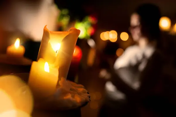 Evde bir kızın yaktığı mumlarla süslenmiş Noel süsleri. Evdeki karanlık, mumların sıcacık parıltısıyla aydınlanıyor. Evin ve dairenin havası ve havası çok güzel. Arka planda iki mum ve ışık var.