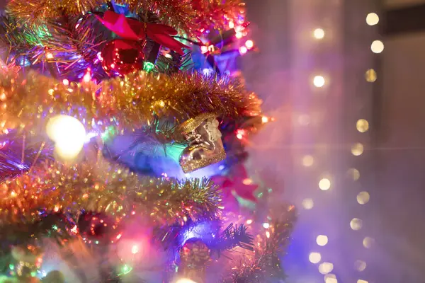 Altın zincirler ve renkli ışıklarla süslenmiş Noel ağacı. Dala Noel Baba 'nın botunun altın bir baloncuğunu asıyor. Sırlarla dolu beyaz dumanlı Noel ağacı. Noel ağacının oksijensiz kalması ya da yanması.