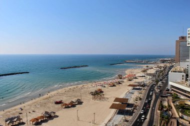 Kumlu plajlar, Akdeniz ve kentsel mimarinin yer aldığı Tel Aviv kıyı şeridinin hava manzarası. Canlı sahnede doğa ve şehir hayatının karışımı, seyahat ve turizm temaları için mükemmel.
