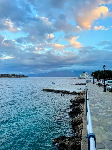 Yunanistan 'ın Girit adasında kıyıya yanaşmış bir yolcu gemisinin bulunduğu pitoresk bir sahil geçidi. Sakin turkuaz sular ve dramatik bir gökyüzü sakin ve manzaralı bir deniz havası yaratır.