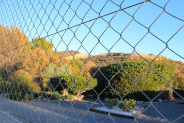 tepeler ve yeşillikler zincirli bir çitin arkasında