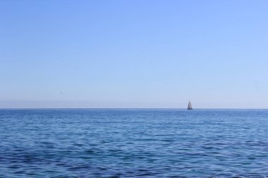 Küçük beyaz bir yelkenli açık güneşli bir günde denize açıldı.