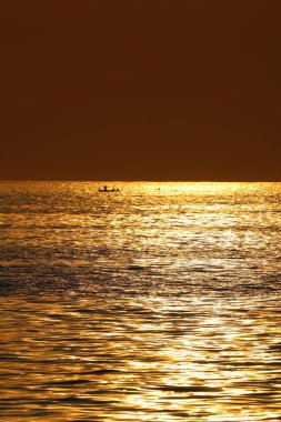 por do sol dourado e homens pescando ao fundo clipart