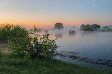 Siste sisli bir gölün üzerinde şafak.