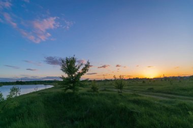 Arkasında ağaçlar olan bir nehrin üzerinde gün batımının güzel bir görüntüsü.