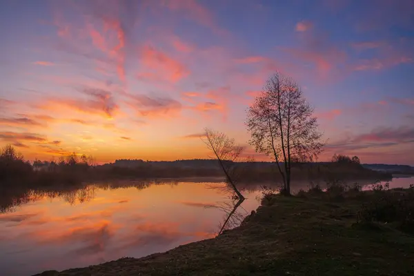 Gölde renkli bir gün doğumu. Renkli ağaçları ve yansıması olan güzel sonbahar manzarası.