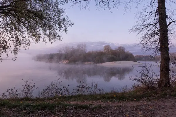 Sonbahar ormanında sisli bir sabahta gün doğumunda göl, bulutlu ve sisli bir göldür.