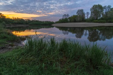 Gün batımında bir ağacın olduğu güzel bir nehir manzarası.