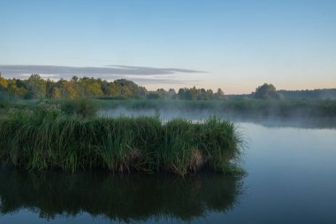 Sakin bir gölün üzerinde sabah sisi.