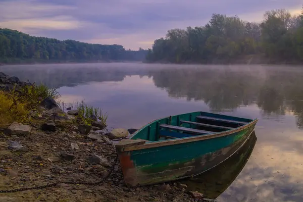 Gün doğumunda sakin bir gölde bir tekne.