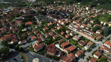 İnsansız hava aracı İtalya 'nın Toskana kentindeki Forte dei Marmi köyünde evlerin üzerinde uçuyor. Arkasında dağlar var. Yüksek kalite 4k görüntü