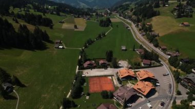 Yazın Alp Dağları 'nın aşağısında küçük bir kasaba. Yol tepeler ve çayırlar boyunca uzanıyor. Saanen, İsviçre... 4 bin dolarlık yüksek kaliteli görüntü.