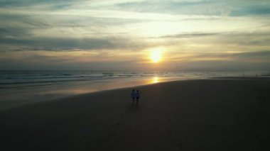 Gün batımında kumsalda yürüyen mutlu bir arkadaşın hava görüntüsü. Yüksek kalite 4k görüntü