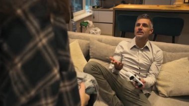 Kır saçlı bir adam elinde joystick ile kanepede otururken kız arkadaşı da ona kirli çamaşırlarını fırlatıyor. Temizlenmediği için hayal kırıklığına uğramış. O, öfkeyle onu azarlıyor. Yüksek kalite 4k görüntü