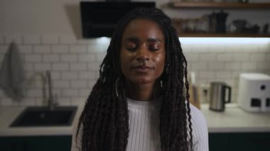 Evde, modern bir mutfakta meditasyon yapan Afro-Amerikan kadın portresi. Yüksek kalite 4k görüntü.