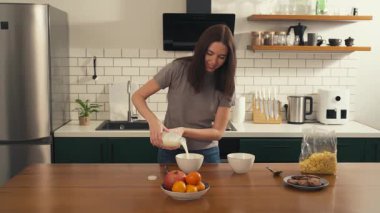 Çok kültürlü bir çift mutfakta birlikte kahvaltı hazırlarken, Afrikalı Amerikalı genç bir adam esmer Avrupalı kız arkadaşına sarılarak mısır gevreği ve süt koyuyor. Yüksek kalite 4k görüntü