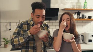 Cozy Kitchen 'da Birlikte Kahvaltı Yapan Çok Kültürlü Çift. Irklar arası Genç Aşıklar Mısır gevreği yiyor, konuşuyor, gülüyor ve sabahları sarılıyorlar. Yüksek kalite 4k görüntü