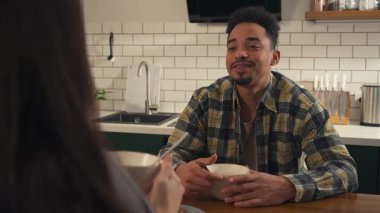 Genç bir adam, güneşli bir mutfağa mısır gevreği dökerken, sabah sıcacık bir an. Yakınındaki biriyle usulca sohbet ediyor. Sıcak, omuzların üstünden bakış açısı daha sade ve sinematik bir hava katıyor. Yüksek kalite 4k görüntü