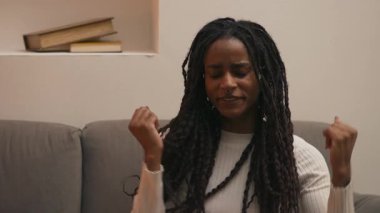 Afrikalı Amerikalı kadın yavaşça kanepeye düşmeden önce esniyor ve esniyor. Kamera hareketlerini takip ediyor. Yüksek kalite 4k görüntü