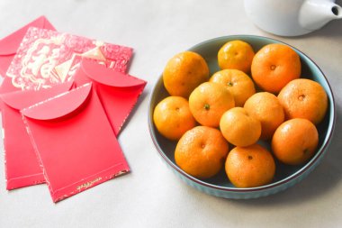 Çin Yeni Yıl dekorasyonu için bir tabak portakal ve bir yığın kırmızı zarf..