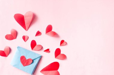 Pembe arka planda kırmızı kalpli zarf ve negatif alan. Sevgililer Günü konsepti.