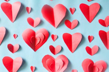Mavi arkaplanda kırmızı kağıt kalpler deseni. Sevgililer Günü geçmişi.